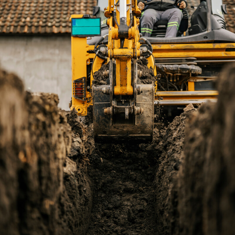 Cropped picture of a backhoe digging soil on construction site and making foundation.